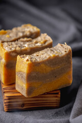 Pieces of natural handmade soap on a wooden soap dish and the dark background
