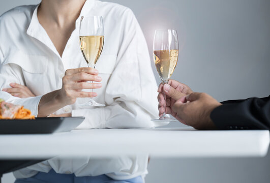No faces of men and women eating in a restaurant or toasting a glass of wine.