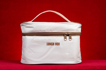 beige color lunch box carrier or insulation bag on a red background