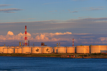 Smokestack over LNG storage tanks at port facility at sunset - 653058099
