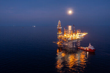 Aerial view of jack up drilling rig in the middle of the ocean while rig move at night time