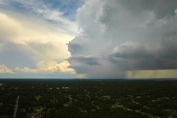 Dark stormy clouds forming on gloomy sky during heavy rainfall season over suburban town area