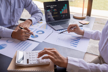 Team businesspeople or an accountant team are analyzing data charts, graphs, and a dashboard on a laptop screen in order to prepare a statistical report and discuss financial data in an office. - obrazy, fototapety, plakaty