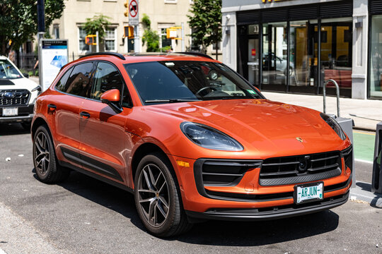 New York City, USA - August 05, 2023: 2023 Porsche Macan T SUV Ruby red car front and side view, parked