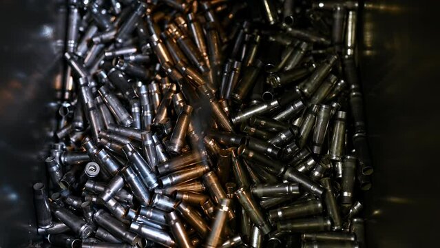 Metal bullet casings fall down into large container at plant