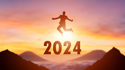 Silhouette of a person leaping from 2023 to 2024 on the top of the mountain background. Happy New Year and Christmas day concept.