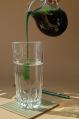 Natural organic green spirulina algae powder drink on neutral beige background. Chlorella seaweed vegan superfood cocktails smoothie supplement source and detox drinking. Innovative ingredient