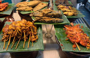 Set of Sundanese side dishes or hidangan sunda, consisting of grilled fish, grilled squid, and...