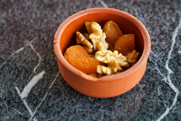 walnut and dried peach fruit on in a small bowl on tiles background 