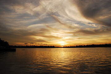 Tropical amazing dramatic golden sky on sunset over scenic river lake seascape ocean. Silhouette tranquil season wilderness serene landscape. Tranquil lake countryside sunrise seaside reflection