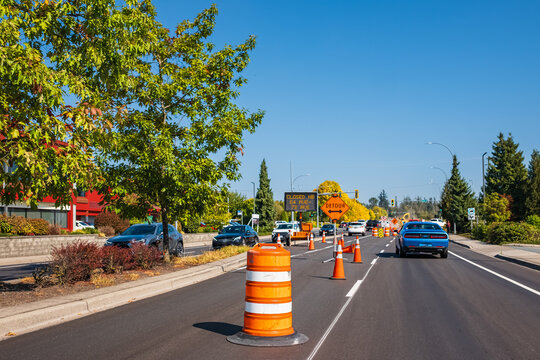 Traffic sign with flags reading Utility Work Ahead with traffic cones on road. Row of Traffic cone in the road repair