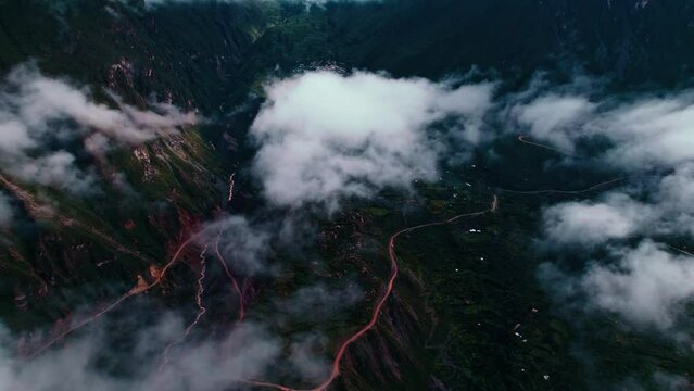 Drone pans left to right, revealing distant Tapay village on a cloudy day with visible roads in the Colca Valley