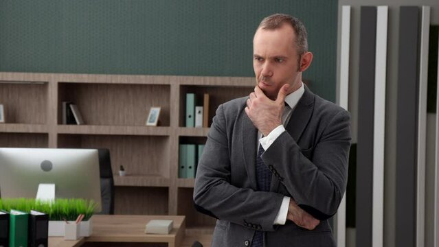 Thoughtful Good-looking Middle-aged Man In Formal Wear Standing In Modern Office, Hands Crossed On Chest. Man Touches His Chin, Thinking Of Problem. High Quality 4k Footage