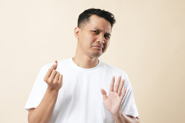 A young Asian man standing with an outstretched hand showing a stop sign, refusing to eat almonds