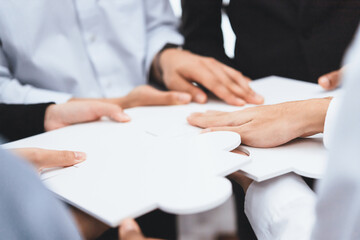 Diverse corporate officer workers collaborate in office, connecting puzzle pieces to represent...