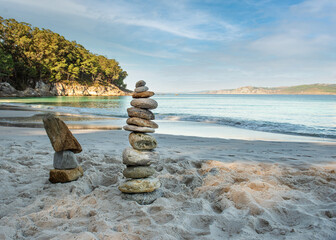 Pyramid stones balance on the sand of the beach. The object is in focus, the background is blurred