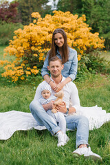 Fototapeta premium Stylish happy young Caucasian family with a young son is walking in the park in the spring