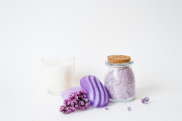 Aromatic spa set. Sea salt for body care, natural soap, candle and lilac flowers on a light background