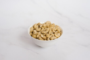 Cashew in a white bowl on a marble table