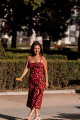 Joyful woman lit by sunlight smiling while enjoying walking outdoors in a park.