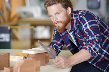 man sanding a wood with sander in a workshop