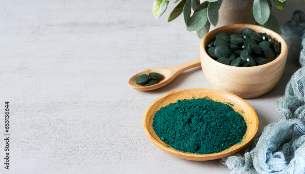 Wall mural spirulina tablet pill powder in wood bowl on white table background. spirulina tablet pill powder on white table background. food healthy spirulina tablet pill powder on white table background.