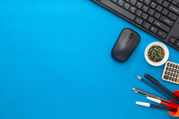 Work desk with black keyboard, mouse, calculator, pen, pencil and plant on a Blue Background....