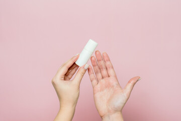 White bottle, drops for eye, nose or ear in hand on pink background. Pharmaceutical product.