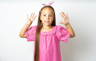 beautiful kid girl wearing pink dress showing and pointing up with fingers number nine while...