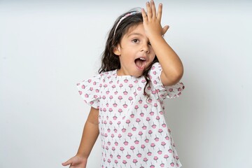 beautiful kid girl wearing dress surprised with hand on head for mistake, remember error. Forgot,...