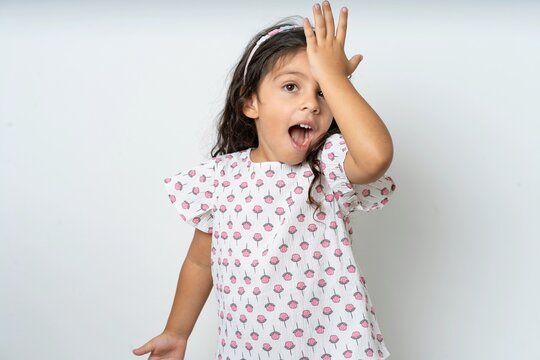beautiful kid girl wearing dress surprised with hand on head for mistake, remember error. Forgot, bad memory concept.