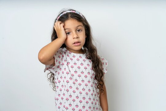 Embarrassed beautiful kid girl wearing dress with shocked expression, expresses great amazement, Puzzled model poses indoor