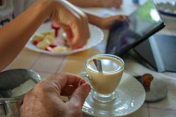 two people having coffee and watching a tablet