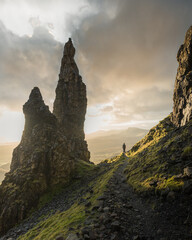 man standing beneath quirang rocks at sunset, isle of skye, scotland