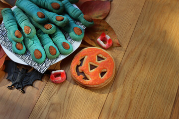 Witch’s fingers and pumpkin cookie for Halloween on a plate on wooden table. Halloween background