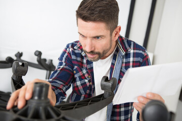 man following instructions to assemble office chair