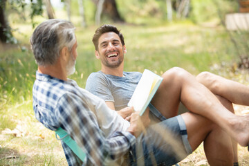 two jovial men relaxing in the countryside with a book