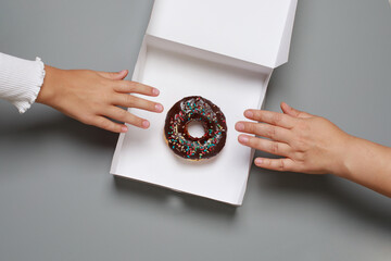 Colorful chocolate donut and hand, top view - Powered by Adobe