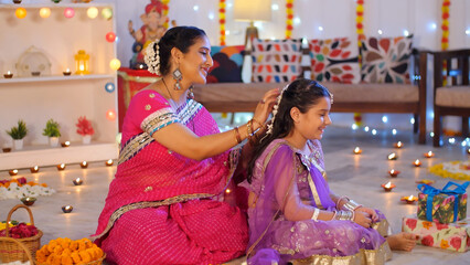 A caring Indian mother putting a beautiful Jaguar on her daughter's hair - Diwali festival  festive...