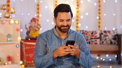 Indian man using a mobile phone - browsing smartphone. Diwali festival celebration. A well-dressed...
