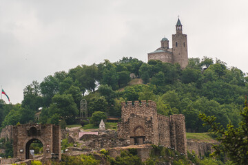 Panorama of the old Bulgarian medieval fortress. A stone bridge leads to an ancient castle on a green hill. A beautiful view of the historical place. Concept of tourism and travel.