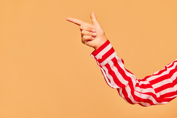 Poster. Female hand showing thumb extended up and index finger extended forward over sand color background.