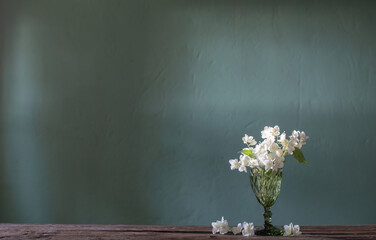 jasmine flowers  in glass vase on green background