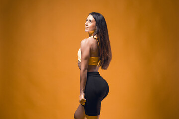 Young sportive attractive caucasian athlete woman posing in yellow tank top and black sauna shorts...