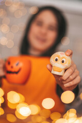 Portrait of candid authentic zoomer boy posing with jack lantern mug and sweets at halloween party