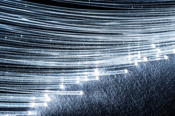 Bundle of optical fibers with lights in the ends. Blue background.