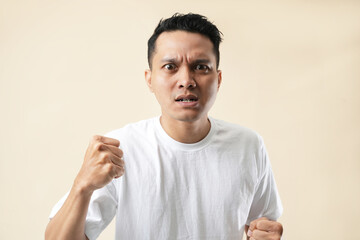 Portrait of an aggressive Asian man, isolated on beige background.