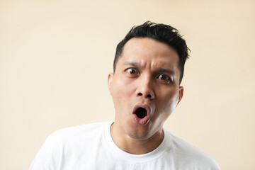 Expression of a furious, enraged Asian man with a grumpy grimace on his face, with mouth opened in...