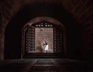 Graceful ballerina performing ballet position in dark passage