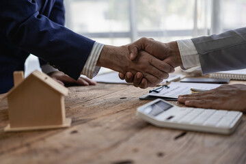 Hands holding hands signing a contract for buying a house or renting a house on a desk Real estate...